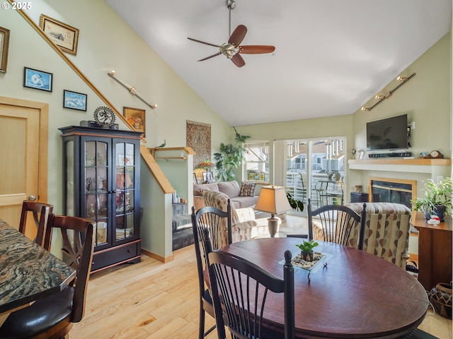 dining space with ceiling fan, high vaulted ceiling, and light wood-type flooring