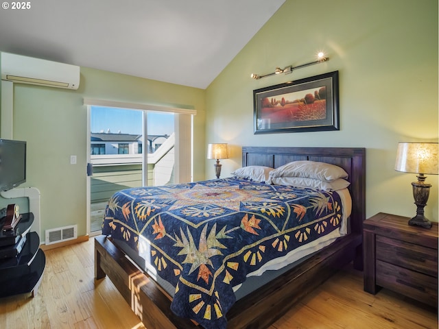 bedroom with lofted ceiling, hardwood / wood-style floors, and a wall mounted AC