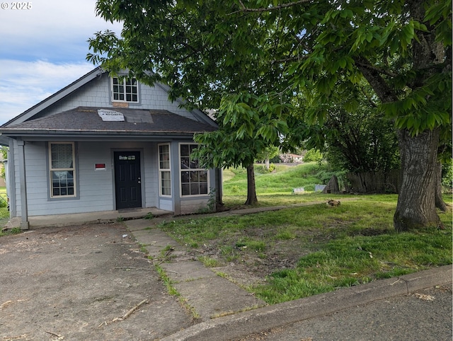 view of front of house with roof with shingles, a porch, and a front lawn