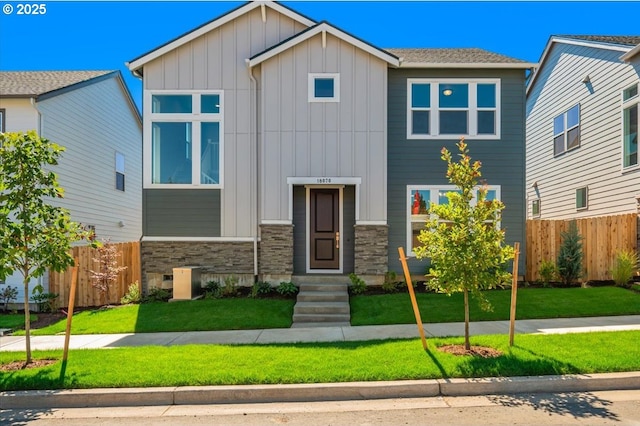 view of front facade featuring stone siding, fence, a front lawn, and board and batten siding