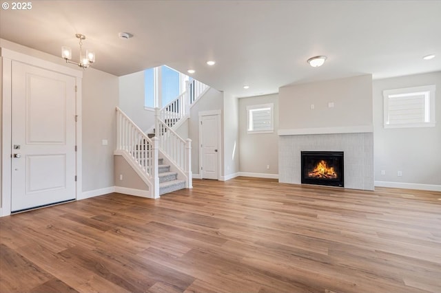 unfurnished living room featuring light wood-type flooring, stairs, baseboards, and a fireplace