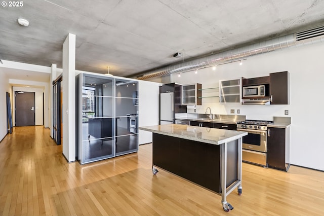 1410 NW Kearney St Unit 717, Portland, OR 97209 - kitchen featuring stainless steel appliances, light wood-type flooring, a center island, glass insert cabinets, and a sink