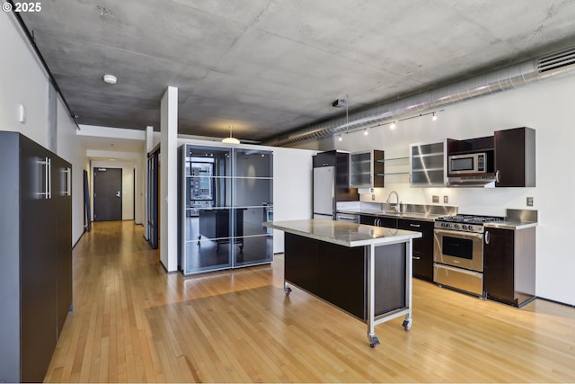 kitchen featuring modern cabinets, stainless steel counters, a kitchen island, stainless steel appliances, and light wood-style floors