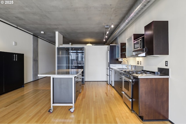 kitchen with a kitchen island, light countertops, light wood-style floors, stainless steel appliances, and modern cabinets