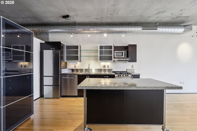 kitchen with stainless steel countertops, light wood-style flooring, appliances with stainless steel finishes, and a sink