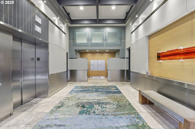 hallway with stone tile floors, coffered ceiling, beam ceiling, elevator, and a towering ceiling