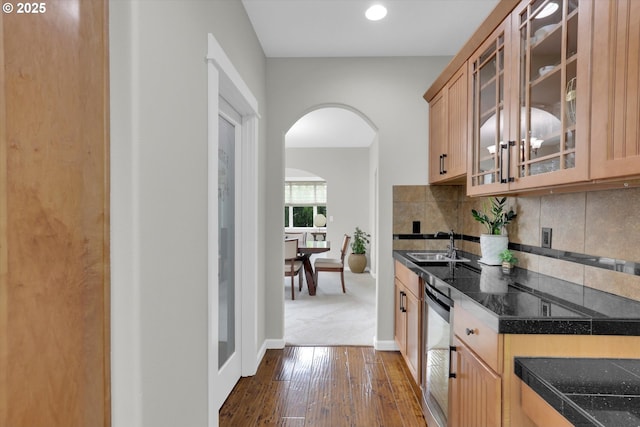 1910 S 15th Cir, Ridgefield, WA 98642 - kitchen with arched walkways, dark wood-type flooring, glass insert cabinets, backsplash, and baseboards