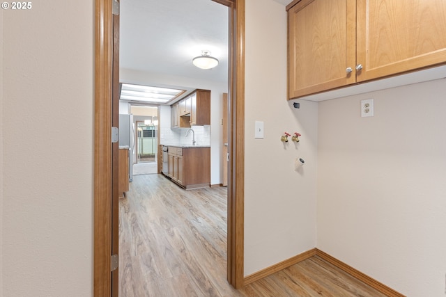 251 NE Village Squire Ave Unit 15, Gresham, OR 97030 - laundry area featuring cabinet space, light wood-style floors, and baseboards