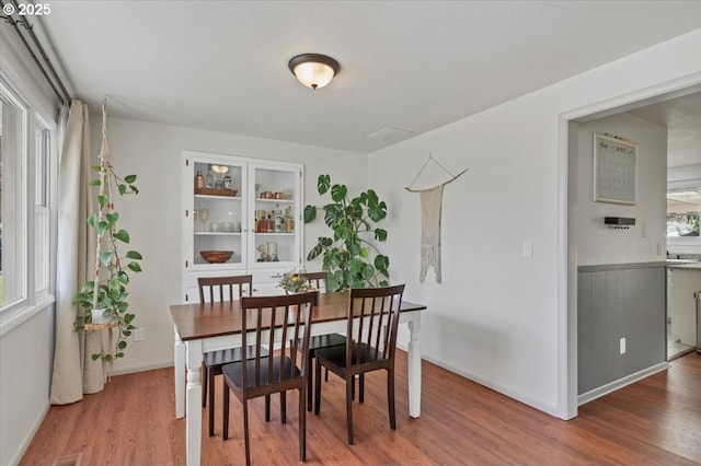 dining space with baseboards and light wood-type flooring