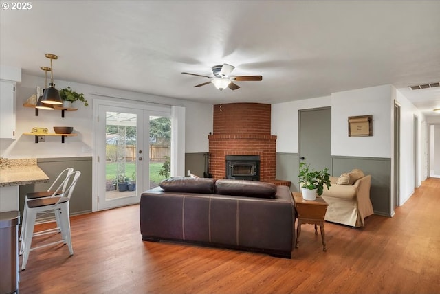 living area featuring light wood-style flooring, a ceiling fan, french doors, and visible vents