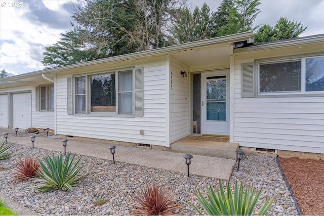 doorway to property with an attached garage and crawl space