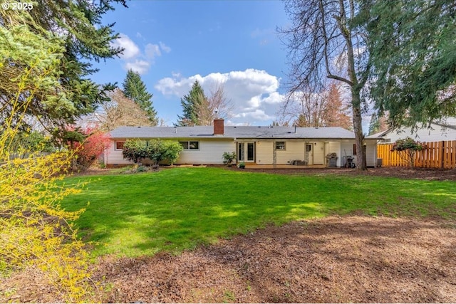 back of property with fence, a patio, a chimney, and a lawn