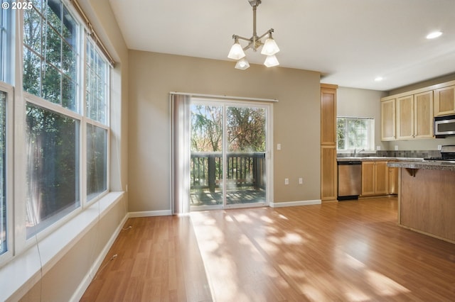 22864 SW Forest Creek Dr Unit 200, Sherwood, OR 97140 - kitchen featuring a chandelier, pendant lighting, light wood finished floors, baseboards, and appliances with stainless steel finishes