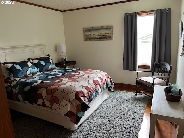 bedroom featuring baseboards, multiple windows, ornamental molding, and wood finished floors