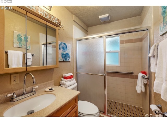 bathroom featuring a stall shower, a textured wall, and a textured ceiling