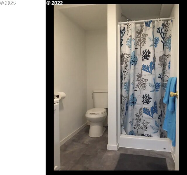 full bath with toilet, baseboards, and a shower stall