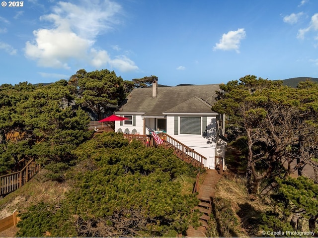 view of front of home featuring a chimney, fence, and stairs