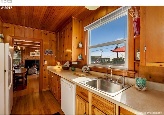 kitchen with dark wood finished floors, white appliances, wood ceiling, wood walls, and a sink