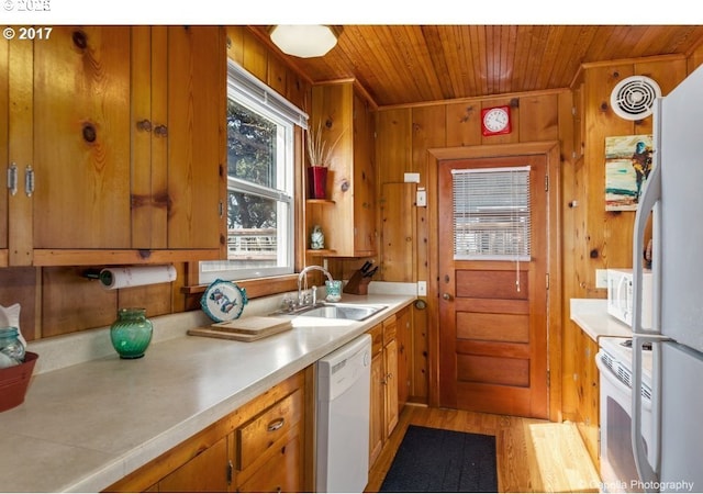kitchen with a sink, light countertops, white appliances, and brown cabinets