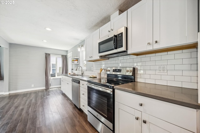 63 S 22nd St, Saint Helens, OR 97051 - kitchen with stainless steel appliances, a sink, dark countertops, baseboards, and dark wood-style floors
