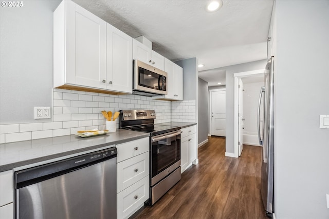 63 S 22nd St, Saint Helens, OR 97051 - kitchen with stainless steel appliances, backsplash, white cabinetry, dark wood-style flooring, and dark countertops