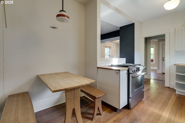 1236 N Emerson St, Portland, OR 97217 - kitchen with stainless steel stove, light wood finished floors, white cabinets, and plenty of natural light