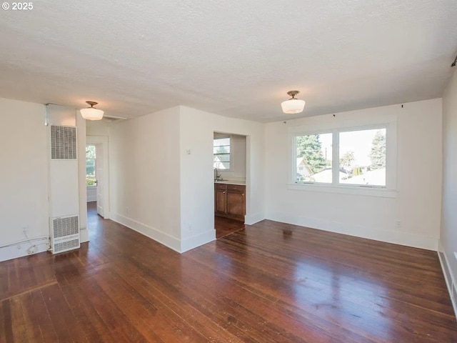 1236 N Emerson St, Portland, OR 97217 - spare room featuring a heating unit, dark wood-style flooring, baseboards, healthy amount of natural light, and a textured ceiling