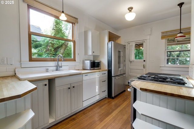1236 N Emerson St, Portland, OR 97217 - kitchen with appliances with stainless steel finishes, butcher block counters, light wood-type flooring, a sink, and healthy amount of natural light