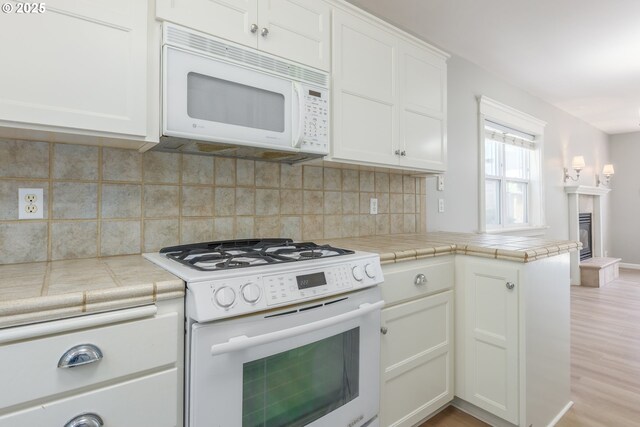 1507 Bogart Ln, Eugene, OR 97401 - kitchen featuring white appliances, white cabinetry, light wood-style floors, backsplash, and tile counters