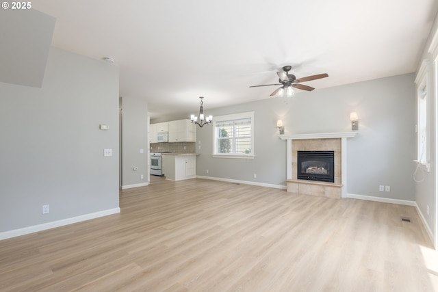 1507 Bogart Ln, Eugene, OR 97401 - unfurnished living room featuring a chandelier, a ceiling fan, a fireplace, and light wood finished floors