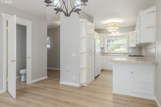 1507 Bogart Ln, Eugene, OR 97401 - kitchen with open shelves, tile countertops, a chandelier, freestanding refrigerator, and white cabinetry