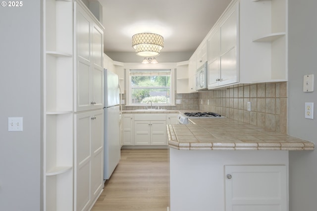 1507 Bogart Ln, Eugene, OR 97401 - kitchen with open shelves, white appliances, decorative backsplash, white cabinets, and light wood-style floors