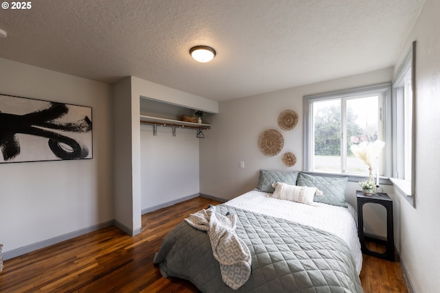 bedroom with a textured ceiling, a closet, wood finished floors, and baseboards