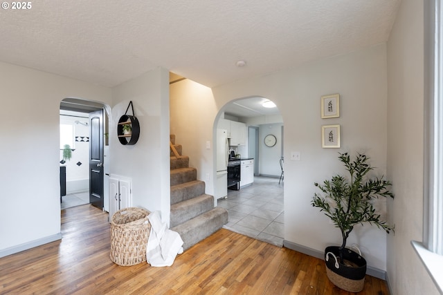 interior space with light wood-style floors, stairs, and arched walkways