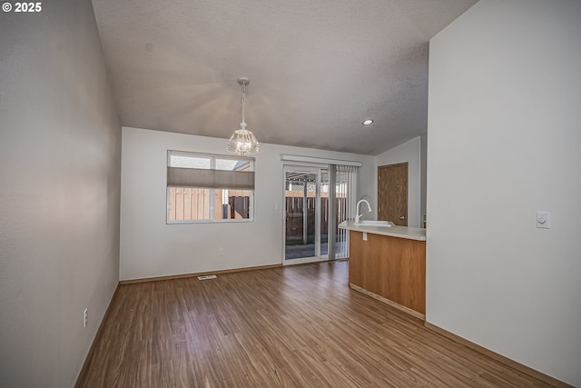 interior space featuring a sink, a textured ceiling, wood finished floors, a chandelier, and baseboards