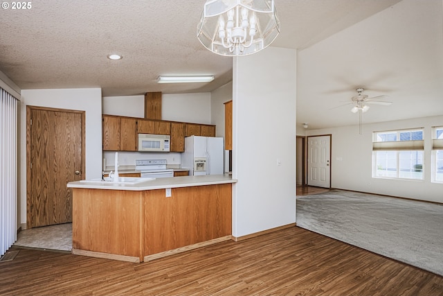 kitchen with lofted ceiling, a textured ceiling, white appliances, wood finished floors, and light countertops