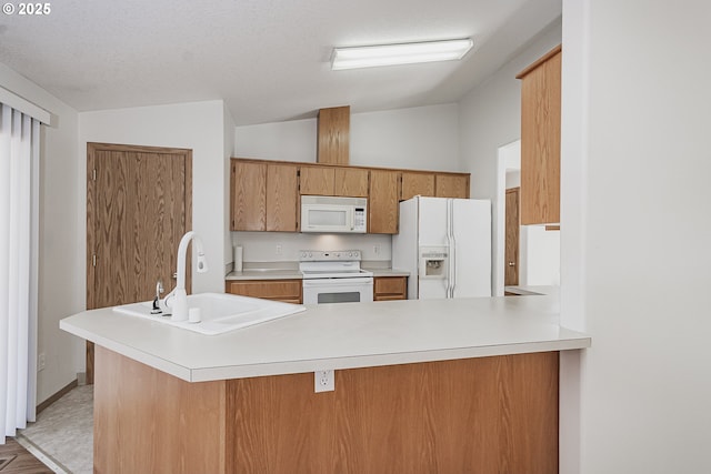 kitchen with brown cabinets, light countertops, vaulted ceiling, a sink, and white appliances