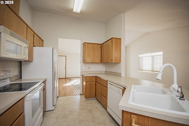 kitchen featuring light floors, light countertops, a sink, white appliances, and a peninsula