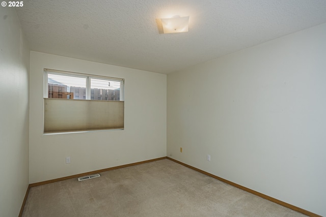 carpeted empty room featuring a textured ceiling, visible vents, and baseboards