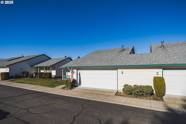 view of front of home with an attached garage, a shingled roof, and a front yard