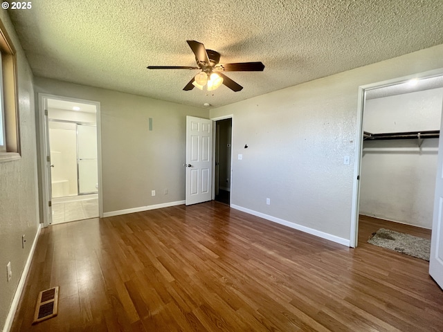 940 W Madrona Ave, Hermiston, OR 97838 - unfurnished bedroom with wood finished floors, a textured ceiling, connected bathroom, a spacious closet, and ceiling fan