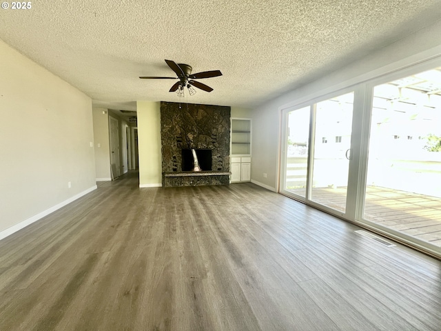 940 W Madrona Ave, Hermiston, OR 97838 - unfurnished living room with wood finished floors, ceiling fan, a textured ceiling, and a stone fireplace
