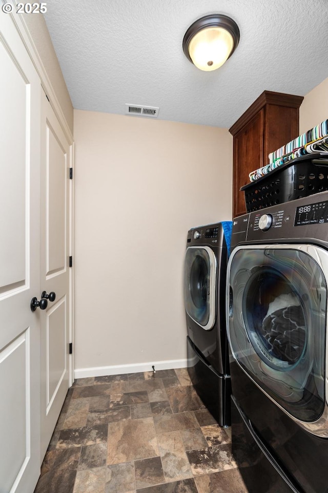 14727 Purple Ash Way, Oregon City, OR 97045 - laundry area featuring washer and clothes dryer, cabinet space, baseboards, dark stone finish flooring, and a textured ceiling