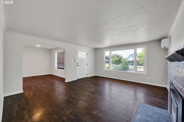 1119 7th St, Springfield, OR 97477 - unfurnished living room featuring wood finished floors, an AC wall unit, a fireplace, arched walkways, and baseboards