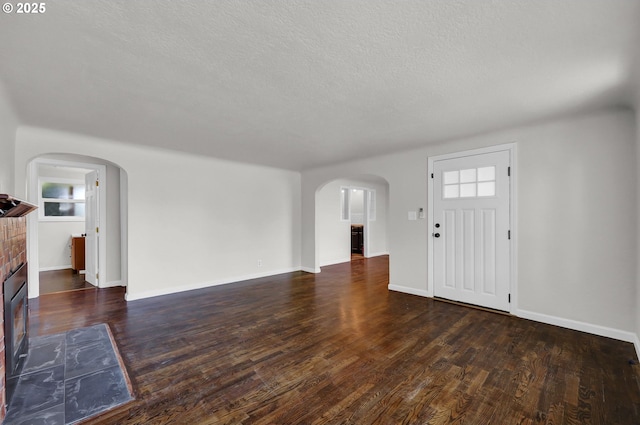 1119 7th St, Springfield, OR 97477 - unfurnished living room with arched walkways, wood finished floors, a textured ceiling, baseboards, and a fireplace