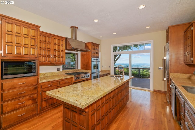 3794 E Nanitch Cir S, Salem, OR 97306 - kitchen with a sink, an island with sink, stainless steel appliances, light wood-style floors, and wall chimney exhaust hood