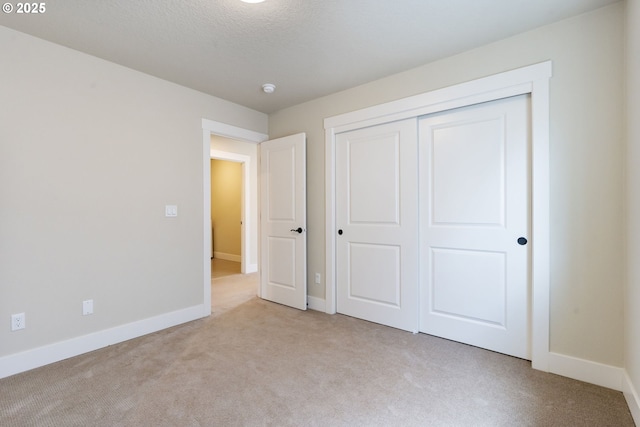 unfurnished bedroom featuring baseboards, carpet, and a closet