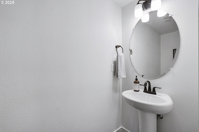 bathroom with a textured wall and visible vents