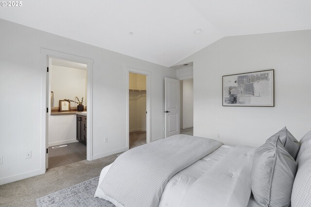 carpeted bedroom featuring lofted ceiling, connected bathroom, baseboards, a spacious closet, and a closet