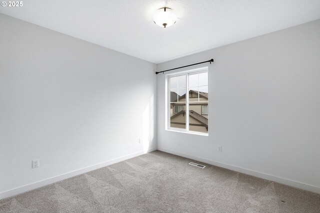 empty room featuring baseboards, visible vents, and carpet flooring